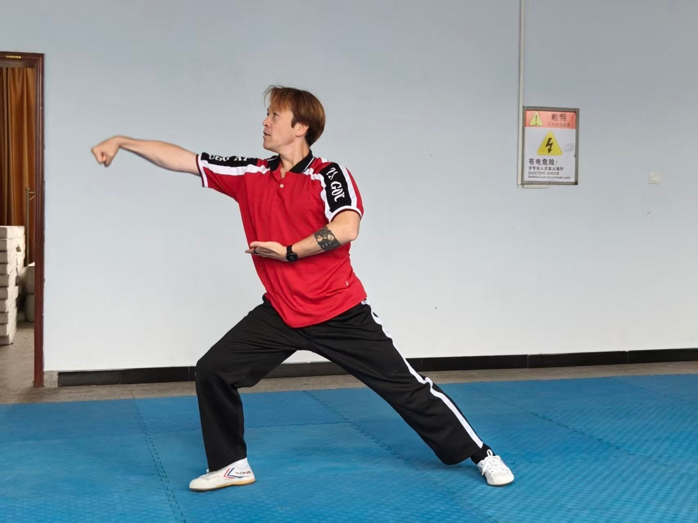 A Shaolin master holding a low stance in a training hall in Dengfeng
