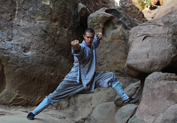 Shaolin monk in a Kung Fu pose on the rocks — training Kung Fu in China as a beginner